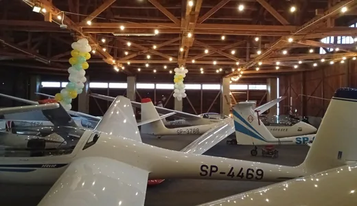 Gliders packed into a hangar under strings of lights