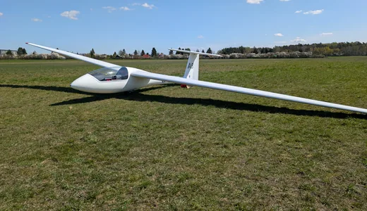 A single-seater standing on the grass, one wing down